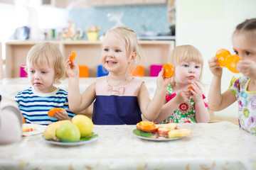 Obraz na płótnie Canvas Funny kids eating fruits in day care centre