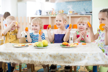 Funny kids eating fruits in kindergarten or day care centre