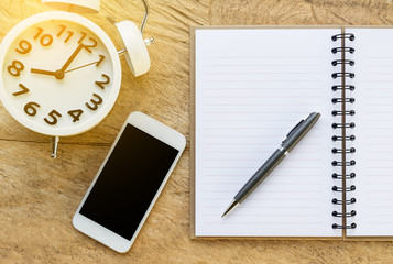 Fototapeta na wymiar ball pen smartphone,mobile alarm clock and open notebook