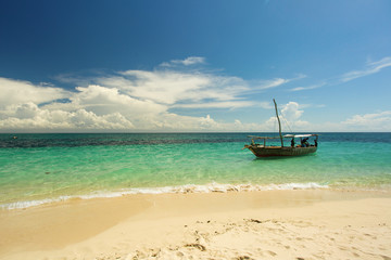 Fototapeta na wymiar Traditional wood boat in Zanzibar with blue sky and white sands