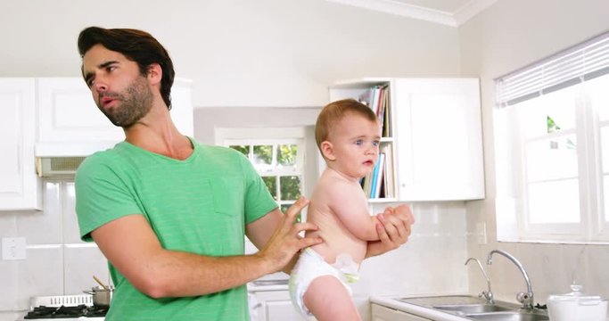 Father grimacing because of need to change baby's nappy