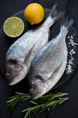 Above view of two raw fresh dorados and seasonings, close-up