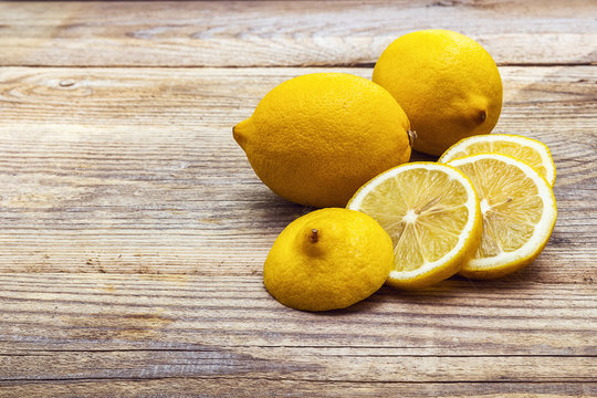 Fresh lemons and lemon slices on grunge wooden boards.