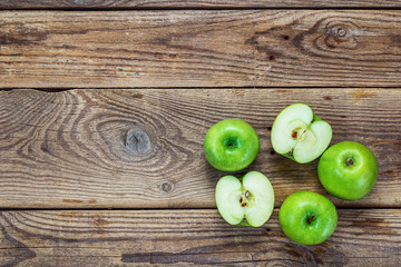 Ripe green apples and apple slices on old wooden background. Pla