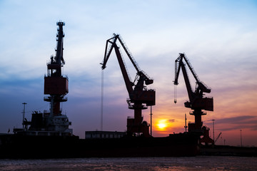 Fototapeta premium In the evening, the silhouette of port cranes