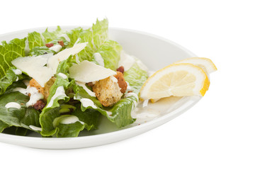 ceasar salad in white plate with lemon slices