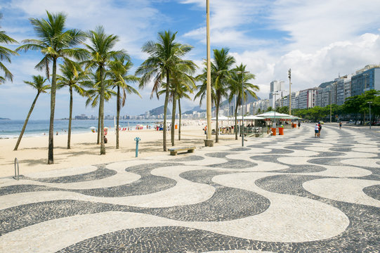 The iconic sidewalk tile pattern of Copacabana Beach curving off into the Rio de Janeiro, Brazil skyline