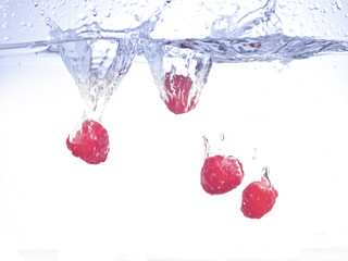 four raspberries falling on water