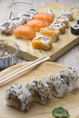 Different Sushi rolls,wasabi and ginger on a plate on wooden bac