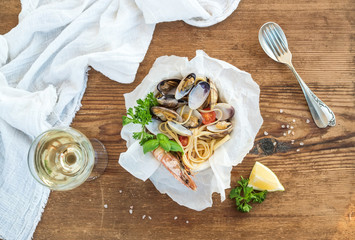 Seafood pasta. Spaghetti with clams and shrimps in bowl, glass of white wine