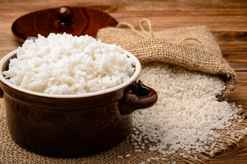 Boiled white rice in ceramic pot on wooden background.
