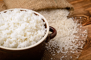 Boiled white rice in ceramic pot on wooden background.