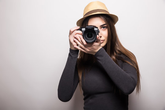 Cute tourist girl taking a photo with a camera on a white background