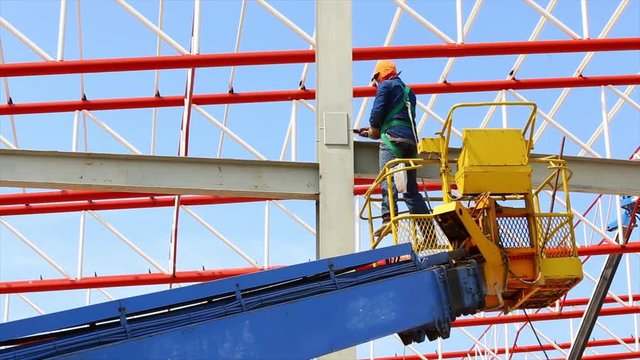 construction worker working at construction site using lifting boom machinery