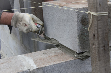 worker aligns with a spatula, lay brick cinderblocks