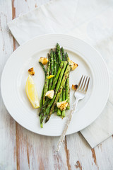 Green Griddled Asparagus with Poached Egg, Lemon and Sourdough Crumbs on a Plate, Light Background