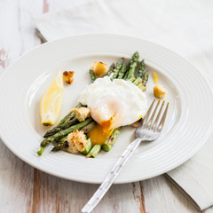 Green Griddled Asparagus with Poached Egg, Lemon and Sourdough Crumbs on a Plate, Light Background