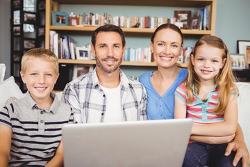 Portrait of happy family using laptop at home