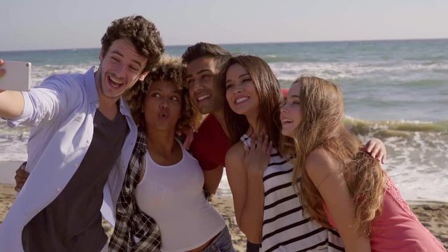 Group of friends made of happy young people having fun while making selfie pictures at the seaside in a warm day of summer