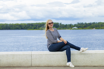 Fototapeta na wymiar Young beautiful woman in blue jeans sitting in summer street par