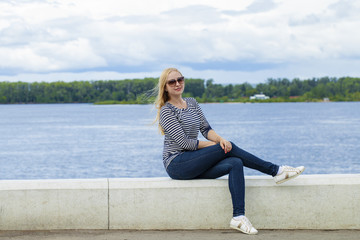 Young beautiful woman in blue jeans sitting in summer street par