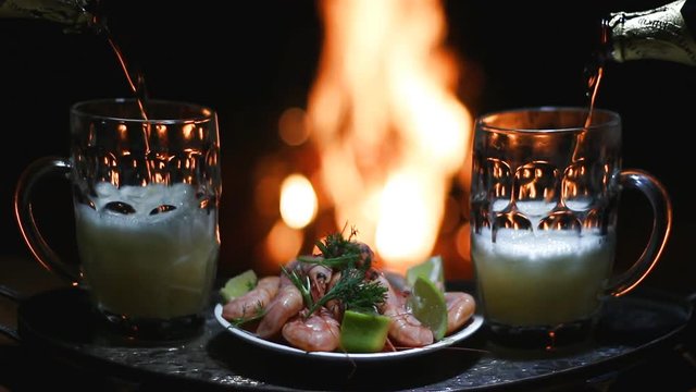 two beers and shrimps with flame on background