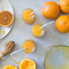 Freshly squeezed orange juice in jar with drinking straw on metallic countertop. Selective focus.