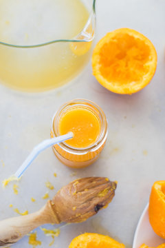 Freshly squeezed orange juice in jar with drinking straw on metallic countertop. Selective focus.