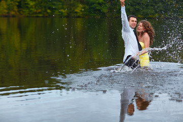 Man splashes water hugging woman in yellow dress