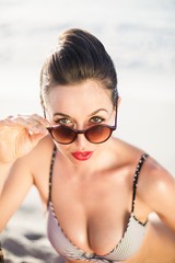 Fototapeta na wymiar Glamorous woman in bikini looking over sunglasses
