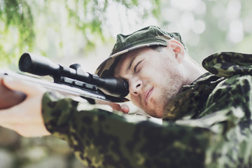 young soldier or hunter with gun in forest