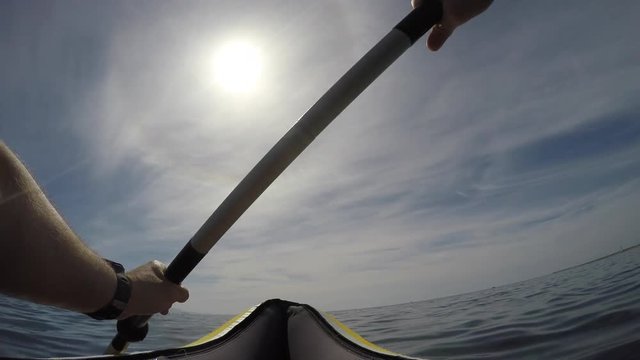 Point of view shot: Man paddling his kayak on calm sea in summer