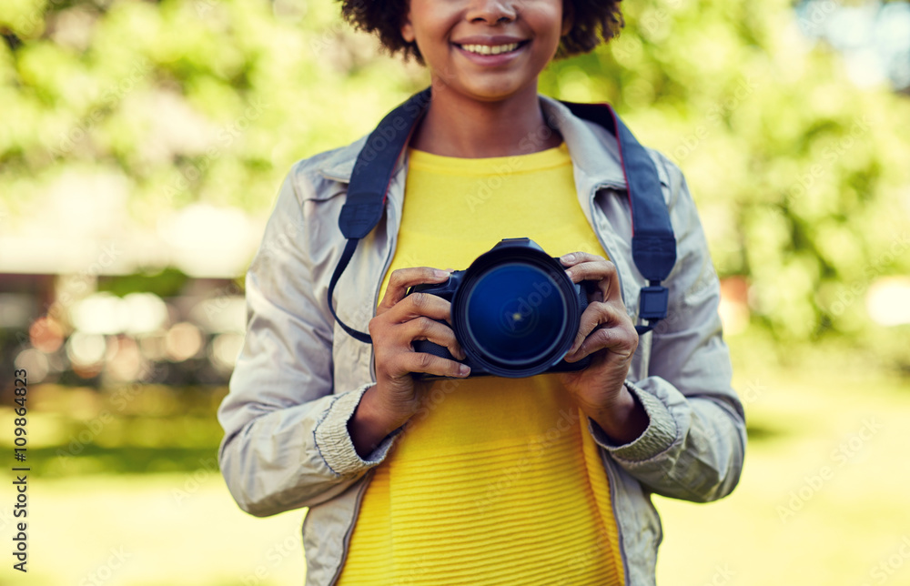 Poster happy african woman with digital camera in park