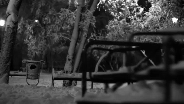 Night Winter Sad empty merry go round spinning in a playground black and white footage