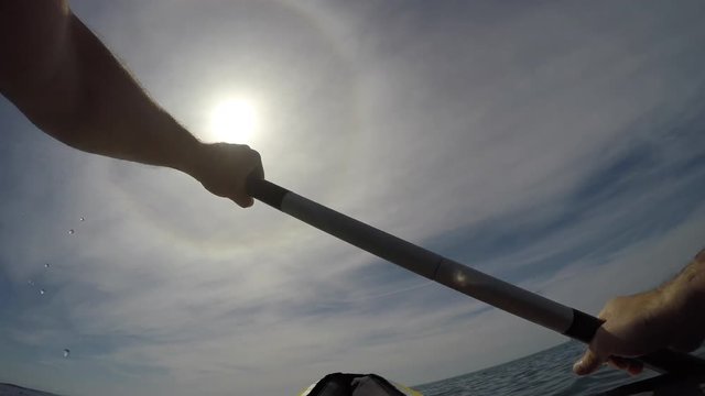 Point of view shot: Man hands on paddle while kayaking at sea in sunshine