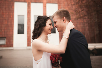 Wedding couple, bride and groom posing near stylish building