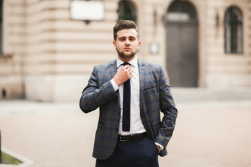 Young stylish businessman adjusting his suit, neck tie