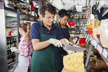 Male Worker Slicing Cheese With Knife In Shop