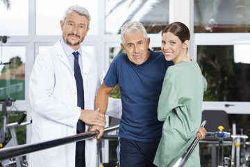 Obraz premium Confident Physiotherapists With Senior Patient In Fitness Studio