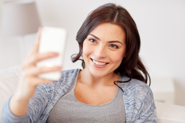 happy woman taking selfie with smartphone at home