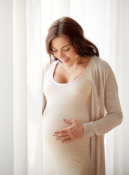 happy pregnant woman with big tummy at home