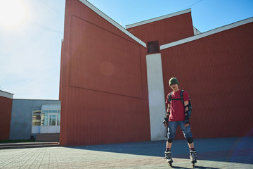 Portrait of a guy in roller skates on a background of red buildings