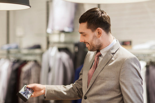 happy young man choosing bow-tie in clothing store