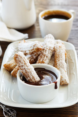 Churros with hot chocolate and powdered sugar.