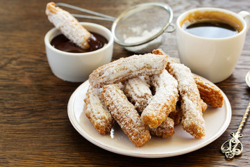 Churros with hot chocolate and powdered sugar.