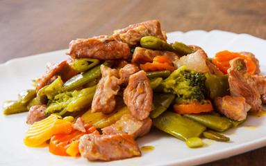 stewed meat with vegetables in a plate on wooden table