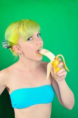 Beautiful girl with green hair eat banana on green background