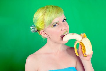 Beautiful girl with green hair eat banana on green background
