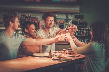 Cheerful multiracial friends having fun eating in pizzeria. - obrazy, fototapety, plakaty