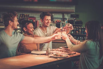 Tuinposter Cheerful multiracial friends having fun eating in pizzeria. © Nejron Photo